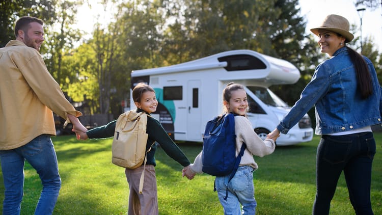 rear-view-of-young-family-with-backpacks-going-to-rv